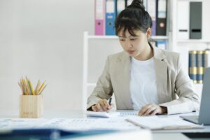 Accountant is working on her desk by using her calculator.