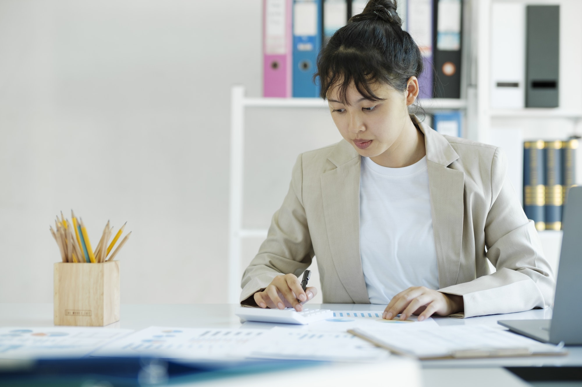 Accountant is working on her desk by using her calculator.
